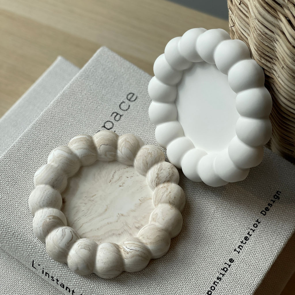 Le plateau bubble présenté en blanc et en marbré beige sur un livre - lifestyle