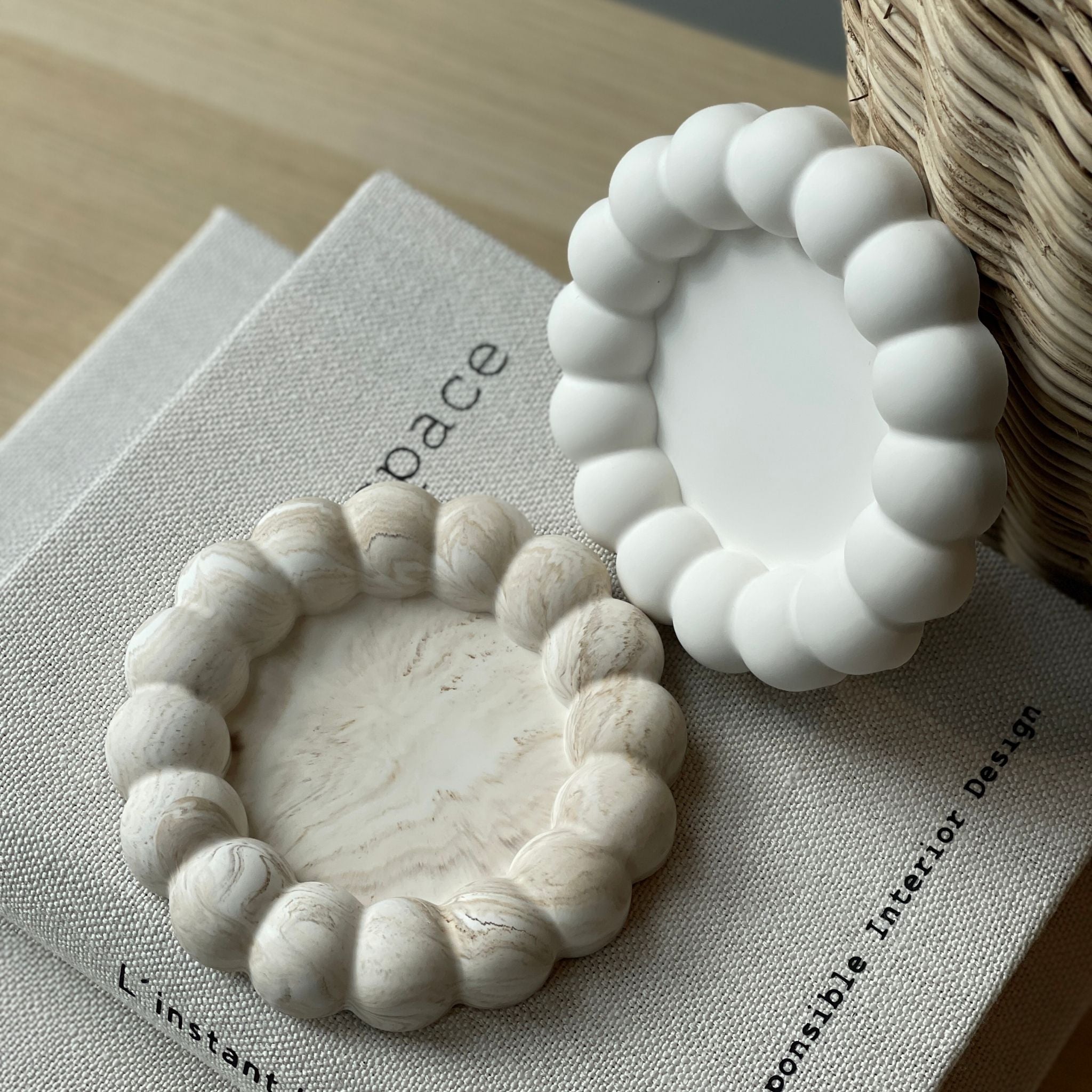 Le plateau bubble présenté en blanc et en marbré beige sur un livre - lifestyle