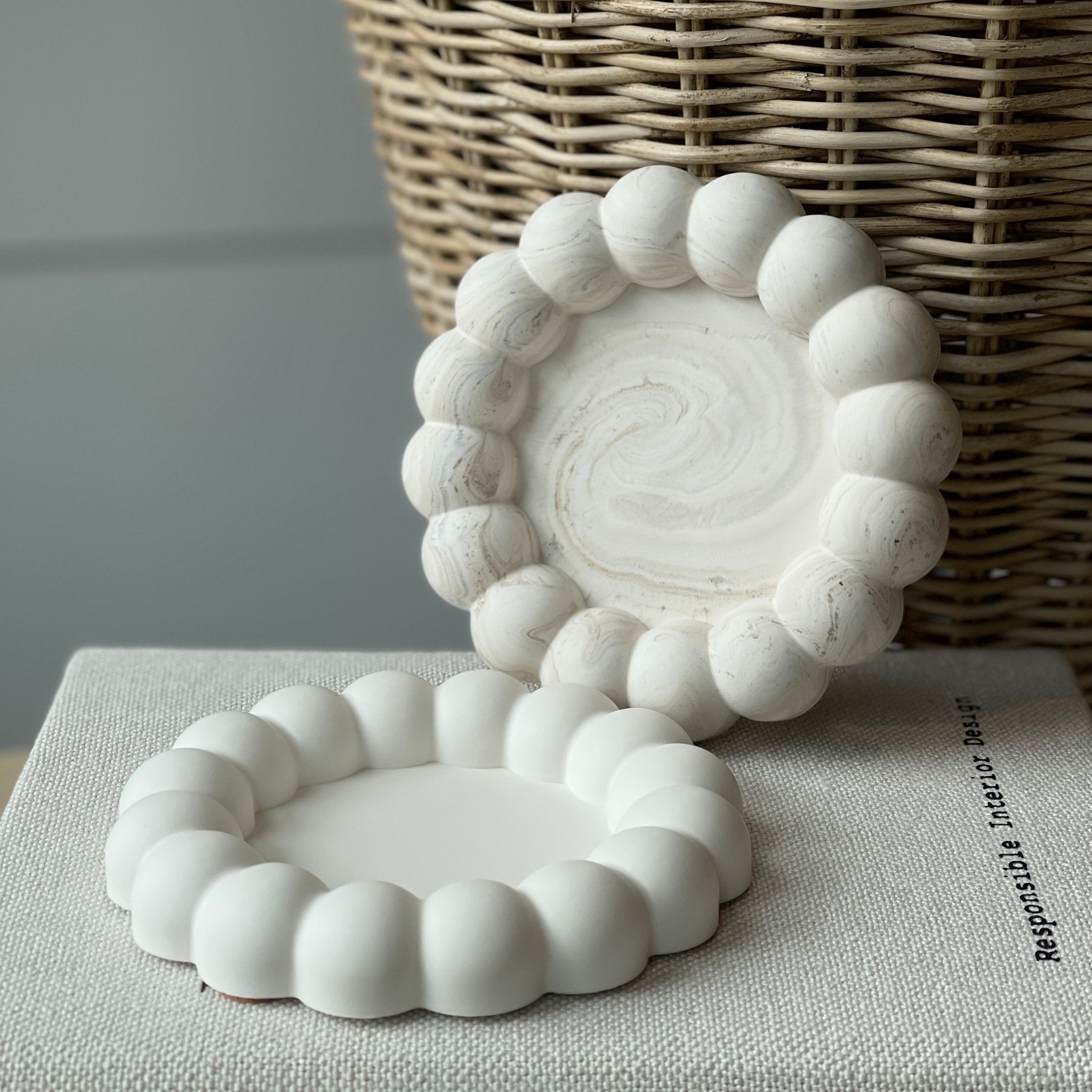 Le plateau bubble présenté en blanc et en marbré beige sur un livre - lifestyle