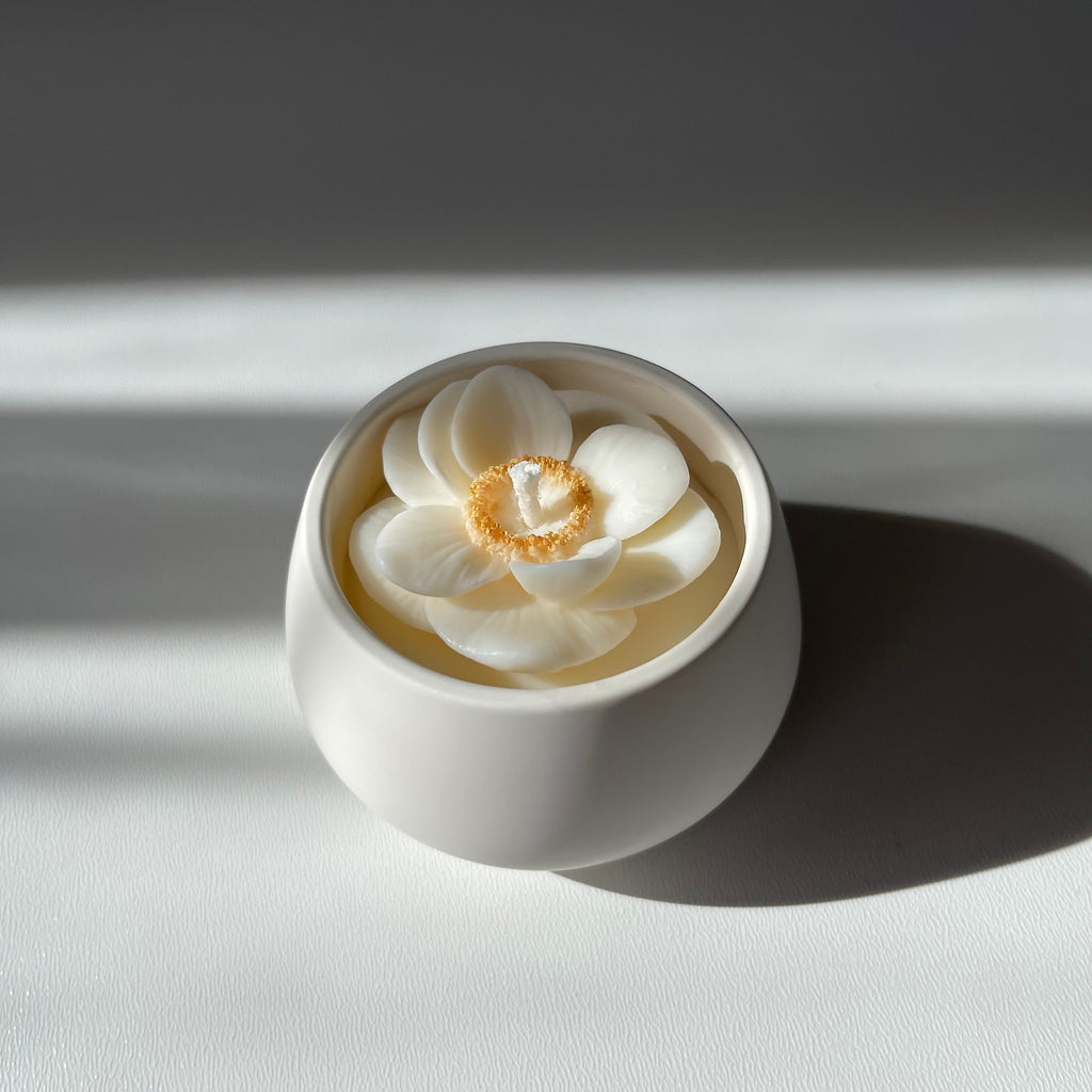 La petite boule blanche "anémone" - bougie parfumée rehaussée d'une fleur anémone coeur doré dans son contenant fait main en jesmonite.