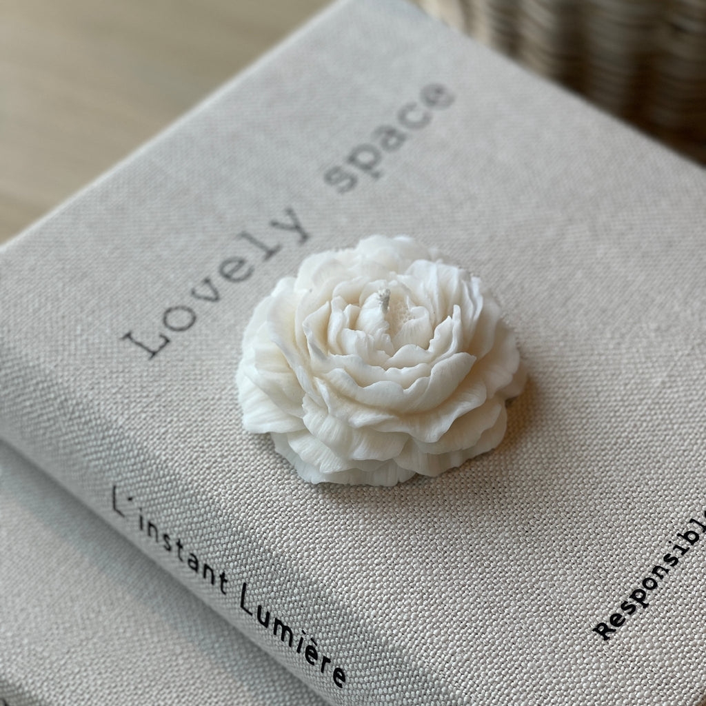 Péony bougie en cire végétale en forme de pivoine déposée sur un livre